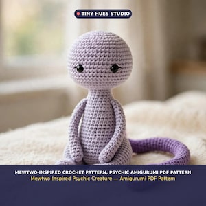 Op de afbeelding: Een lichtpaars gehaakt amigurumi-wezen met een grote ronde kop, kleine zwarte ogen en een lange staart. De tekst luidt: TINY HUES STUDIO, MEWTWO-INSPIRED CROCHET PATTERN, PSYCHIC AMIGURUMI PDF PATTERN, Mewtwo-Inspired Psychic Creature — Amigurumi PDF Pattern.