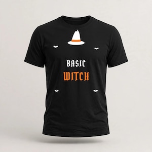 May include: A black short-sleeved t-shirt featuring a white witch hat with an orange band at the top. Below the hat, the text reads BASIC in white and WITCH in orange. Four small white bat silhouettes are positioned around the central text.