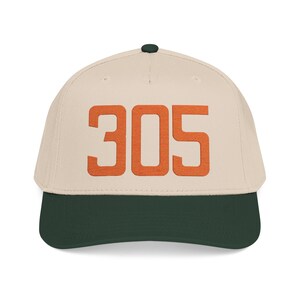 May include: A beige baseball cap with a dark green brim and a dark green button on top. The front of the cap features the number 305 embroidered in a bold, orange, block-style font. The cap has a structured crown and stitched eyelets.