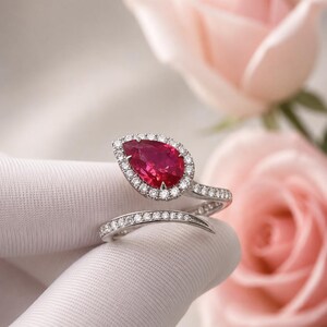 Elegante anello da donna con rubino, gemma rossa a goccia con doppio anello scintillante e alone di diamanti.