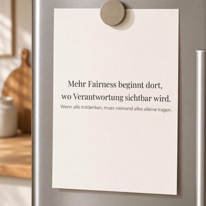 May include: A rectangular off-white paper note held by a circular matte beige magnet on a metallic surface. The text reads: Mehr Fairness beginnt dort, wo Verantwortung sichtbar wird. Wenn alle mitdenken, muss niemand alles alleine tragen.