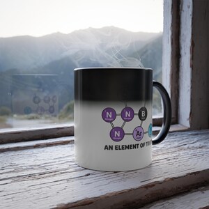 May include: A black and white ceramic mug featuring a chemical structure diagram with purple, black, and blue circular icons labeled with chemical symbols and names, including the text AN ELEMENT OF TRUTH printed in black capital letters.