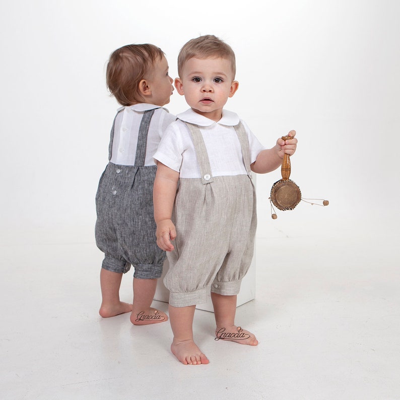 Puede incluir: Dos ni&ntilde;os peque&ntilde;os con camisas blancas de manga corta con cuello redondo y petos de estilo lino. Un peto es de color gris oscuro y el otro es de color beige claro. Los petos cuentan con tirantes abotonados y un dise&ntilde;o frontal plisado.
