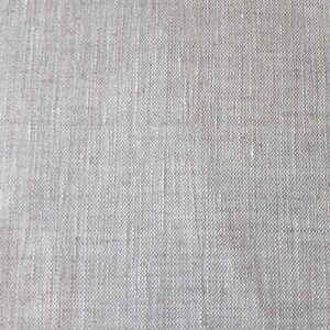 Puede incluir: Una vista de cerca de una tela de color beige claro con una textura tejida visible. El material presenta un patr&oacute;n de cuadr&iacute;cula consistente creado por hilos entrelazados, mostrando variaciones naturales en el grosor y color de las fibras.