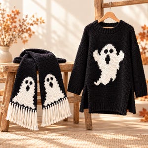 Può includere: Un maglione nero a maniche lunghe e una sciarpa abbinata, entrambi caratterizzati da un motivo a fantasma bianco. Il maglione presenta uno scollo rotondo e spacchi laterali, mentre la sciarpa è rifinita con lunghe frange bianche alle estremità.