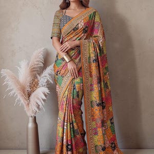 May include: A multi-colored patchwork saree featuring a vibrant array of orange, pink, green, and blue geometric patterns. The fabric is adorned with intricate embroidery and small reflective mirror accents along the borders and throughout the design.