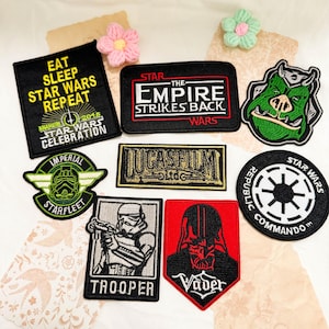May include: A collection of eight embroidered Star Wars themed patches featuring various designs including text such as Eat Sleep Star Wars Repeat, The Empire Strikes Back, Lucasfilm Ltd, Trooper, Vader, and Republic Commando, alongside character icons.