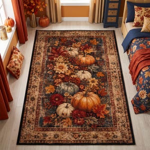 May include: A rectangular area rug featuring a central design of orange, white, and grey pumpkins surrounded by autumn leaves and flowers. The rug has a dark blue background and a wide, decorative border in shades of tan, brown, and deep red.