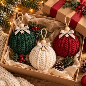 May include: Three round crochet ornaments in dark green, cream, and deep red, each topped with a wooden bead, a beige fabric bow, a small wooden star, and a jute hanging loop, presented in a gift box with tissue paper and pine accents.