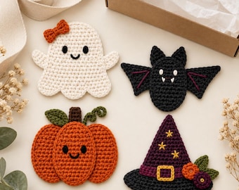 May include: Four crocheted appliqués featuring a white ghost with an orange bow, a black bat with white fangs, an orange pumpkin with a green stem, and a purple witch hat with yellow stars and a gold buckle, arranged on a light surface.