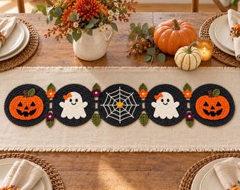 May include: A crochet table runner featuring five circular motifs connected by small flowers and leaves. The design includes two orange jack-o'-lanterns, two white ghosts with orange bows, and a central white spider web on a black background.