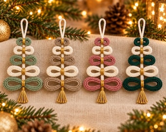 May include: Four macrame Christmas tree ornaments featuring looped cord designs in sage green, beige, dusty rose, and dark green. Each tree has a central vertical cord with gold-coloured accents, a hanging loop at the top, and a small tassel at the base.