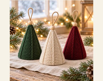 May include: Three cone-shaped crochet ornaments in dark green, cream, and deep red. Each features vertical ribbed detailing, a natural wooden bead at the top, and a jute twine hanging loop. Text reads: MISHWEAR Woodland Mini Trees.