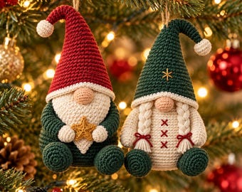 May include: Two crochet gnome ornaments hanging from strings. The left gnome wears a red hat and holds a gold star. The right gnome wears a dark green hat, has braided hair, and features a cream-coloured body with red cross-stitch detailing.