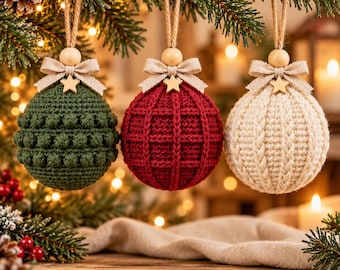 May include: Three spherical crochet ornaments hanging from a pine branch. The left is dark green with bobble stitches, the center is deep red with a grid pattern, and the right is cream with cable knit textures. Each has a beige bow and star.