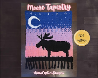 Puede incluir: Un tapiz de ganchillo rectangular con la silueta de un alce negro sobre un fondo degradado en azul, morado y rosa. El diseño incluye una luna creciente blanca, estrellas y flecos negros. El texto dice Moose Tapestry, PDF pattern y AbiesCustomDesigns.