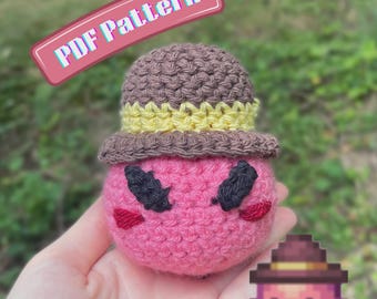 Puede incluir: Un juguete de peluche tejido a ganchillo de color rosa, con un sombrero marrón con una banda amarilla, cejas negras bordadas y pequeños acentos rojos en las mejillas. La imagen incluye el texto PDF Pattern y AbiesCustomDesigns e icono.