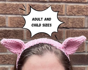 Puede incluir: Una diadema de ganchillo de color rosa claro con dos orejas puntiagudas de estilo animal a los lados. Un gráfico de burbuja de texto blanco se sitúa sobre la diadema con el texto negro ADULT AND CHILD SIZES impreso claramente en el centro.