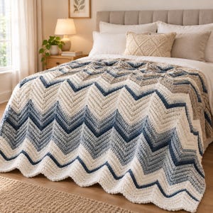 Può includere: Una coperta all'uncinetto con motivo a chevron nei toni del crema, azzurro e blu navy scuro. Il filato testurizzato crea un design a zigzag ripetuto che copre il letto, completato da un cuscino decorativo color crema.