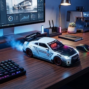 Peut inclure: Un modèle de voiture de sport blanc et noir avec un aileron arrière portant le texte Top Secret, des jantes rouges et un affichage d'horloge numérique sur le pare-brise indiquant 23:59. La voiture émet une brume bleue et a des phares allumés.