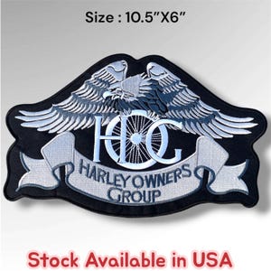 May include: A black embroidered patch featuring a spread-winged eagle above the letters HOG, with a motorcycle wheel integrated into the letter O. A banner below reads HARLEY OWNERS GROUP. The patch measures 10.5 inches by 6 inches in size.