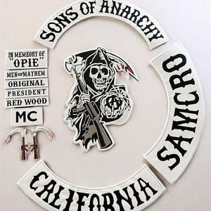 May include: A set of embroidered patches featuring a central grim reaper figure holding a rifle and scythe, surrounded by curved white rockers with black text reading SONS OF ANARCHY, SAMCRO, and CALIFORNIA, plus smaller rectangular name patches.