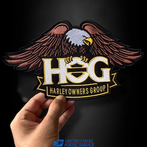 May include: An embroidered patch featuring a bald eagle with brown wings and a white head above the text HOG and HARLEY OWNERS GROUP in white and yellow lettering. The design includes a shield emblem and black borders on a dark background.