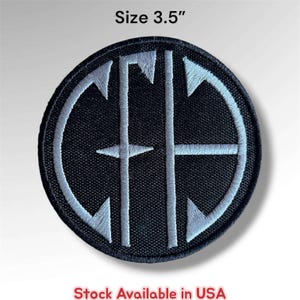 May include: A circular black embroidered patch featuring a white monogram design with the letters C, F, and G intertwined. The patch has a diameter of 3.5 inches. The design consists of clean, straight lines and sharp geometric points within a circular border.