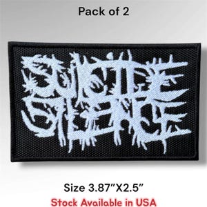 May include: A rectangular black embroidered patch featuring white stylized text that reads Suicide Silence. The patch measures 3.87 inches by 2.5 inches. This is a pack of 2 patches with a black border and a textured fabric base.