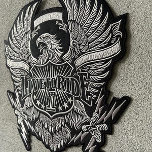 May include: A black and white embroidered patch featuring a large eagle with spread wings. The design includes the text "FREEDOM", "LEGENDARY", "MOTORCYCLES", and "LIVE TO RIDE" with a central shield displaying the number "1" and stars.
