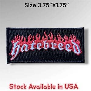 May include: A rectangular embroidered patch with a black background featuring the word "hatebreed" in light blue gothic-style lettering, topped with red flames. The patch measures 3.75 inches by 1.75 inches and has a black stitched border.