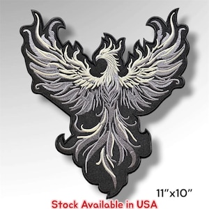 May include: An embroidered patch featuring a stylized phoenix with wings spread wide. The design uses shades of white, light gray, and dark gray thread against a black background. The patch measures 11 inches by 10 inches as indicated by text.