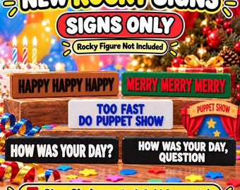 May include: Five rectangular signs with raised lettering. One brown sign reads HAPPY HAPPY HAPPY, one green sign reads MERRY MERRY MERRY, one white sign reads TOO FAST DO PUPPET SHOW, and two black signs read HOW WAS YOUR DAY? and HOW WAS YOUR DAY, QUESTION.