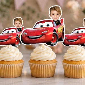 Peut inclure: Trois cupcakes surmontés de décorations personnalisées représentant une voiture de course rouge avec le numéro 95 et le visage découpé d'un enfant. La voiture a de grands yeux sur le pare-brise, une bouche souriante et des pneus noirs.