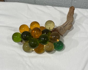 Very large cluster of green and yellow grapes attached to driftwood.