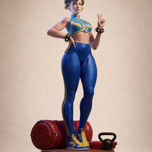 Puede incluir: Una figura coleccionable de un personaje con cabello castaño en moños, vistiendo un top azul y amarillo sin mangas, leggings azules y zapatillas a juego. La figura lleva brazaletes con pinchos, hace el signo de la paz y está sobre una base.