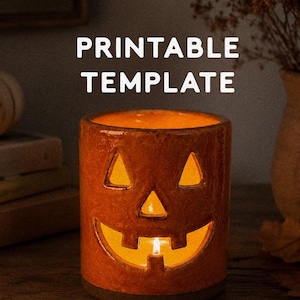 May include: A cylindrical orange ceramic jack-o'-lantern candle holder with cut-out eyes, nose, and mouth, illuminated from within by a warm light. The text PRINTABLE TEMPLATE is centered above, and digital download is at the bottom.