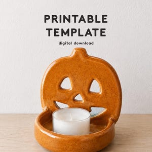 Könnte beinhalten: Ein glänzender, orangefarbener Kerzenhalter aus Keramik in Kürbisform mit ausgeschnittenen Augen und Nase, der ein kleines weißes Teelicht enthält. Der Text PRINTABLE TEMPLATE digital download steht oben, CLAY LIBRARY CO. unten.