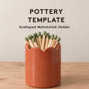 May include: A terracotta-coloured ceramic matchstick holder with a scalloped top edge, filled with wooden matches featuring sage green tips. The text POTTERY TEMPLATE Scalloped Matchstick Holder is printed above the holder in dark brown letters.