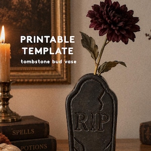 Può includere: Un vaso soliflore nero a forma di lapide con le lettere RIP in rilievo sul davanti e un design a crepe. Il testo PRINTABLE TEMPLATE tombstone bud vase è visibile. Un fiore bordeaux scuro è inserito nel vaso, che presenta una finitura ruvida.