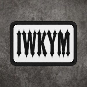 May include: A rectangular embroidered patch featuring a white background with a thick black border. The letters IWKYM are stitched in a bold, black, gothic-style font across the centre of the patch, creating a high-contrast design.