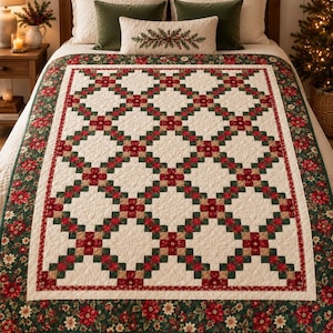 May include: A quilt featuring a cream-colored background with a repeating grid pattern of red and green squares. The border is decorated with a floral print of red and white poinsettias on a dark green background, finished with a quilted texture.
