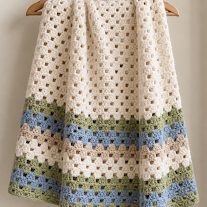 May include: A handmade crochet blanket featuring a classic granny square pattern. The design consists of a large cream-colored section at the top, followed by horizontal stripes in sage green, light blue, and beige, ending with a green border.