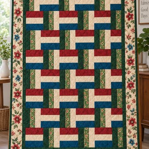 May include: A rectangular quilt featuring a repeating block pattern of red, blue, and cream rectangles separated by green floral strips. The quilt is framed by a wide border with a cream background and a pattern of red and blue flowers.
