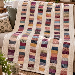May include: A quilt featuring vertical columns of multi-colored fabric strips in various floral and geometric patterns, separated by solid cream-colored fabric sashing. The quilt has a textured, stitched surface and includes the text CraftsPatterns.club.