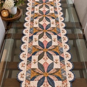 May include: A long, rectangular quilted table runner featuring a repeating floral pattern with scalloped edges. The design incorporates shades of blue, mustard yellow, pink, and cream, with intricate stitching details forming flower motifs.