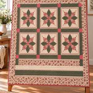Könnte beinhalten: Ein rechteckiger Quilt mit sechs quadratischen Blöcken in zwei Reihen. Jeder Block zeigt ein zentrales Sternmuster in Dunkelgrün und gedämpftem Rot auf cremefarbenem Grund. Der Quilt ist mit einem Blumenmuster und horizontalen Streifen umrandet.