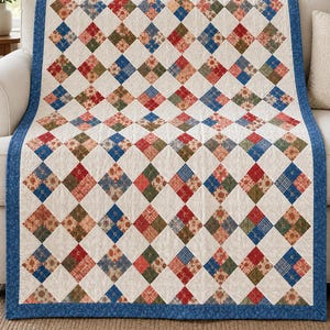 May include: A rectangular quilt featuring a repeating pattern of diamond-shaped fabric patches in shades of red, blue, and green, separated by white quilted sections. The entire piece is framed by a solid blue border with a floral print.