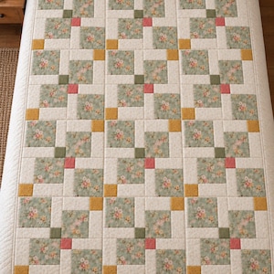 May include: A rectangular quilt featuring a repeating grid pattern of cream-colored fabric squares interspersed with floral-printed squares in sage green, accented by small solid squares in mustard yellow, olive green, and coral pink.