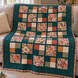 May include: A patchwork quilt featuring a grid of alternating squares. The design includes floral patterns in shades of pink, orange, and green, solid cream squares, and textured dark teal fabric. The quilt is finished with a dark teal border.